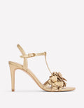 Gold high-heeled sandal with floral design on a white background