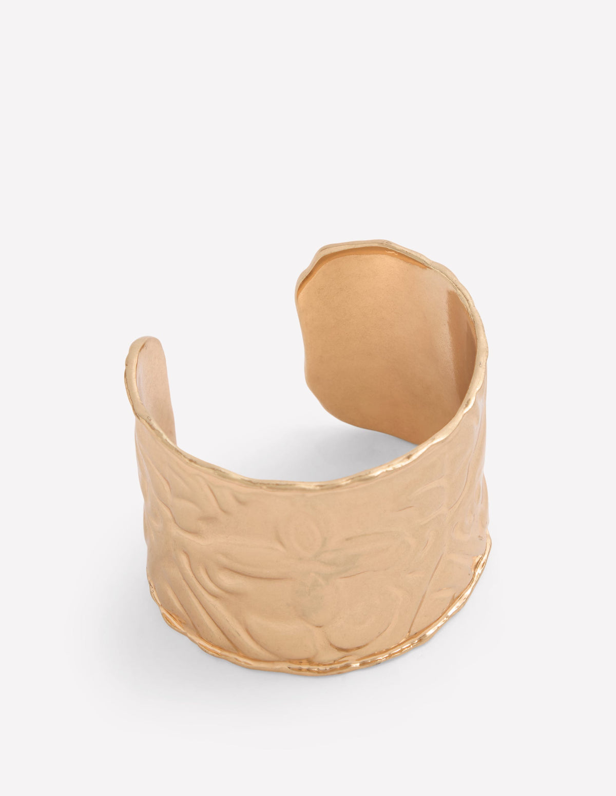 Gold cuff bracelet on a light gray background