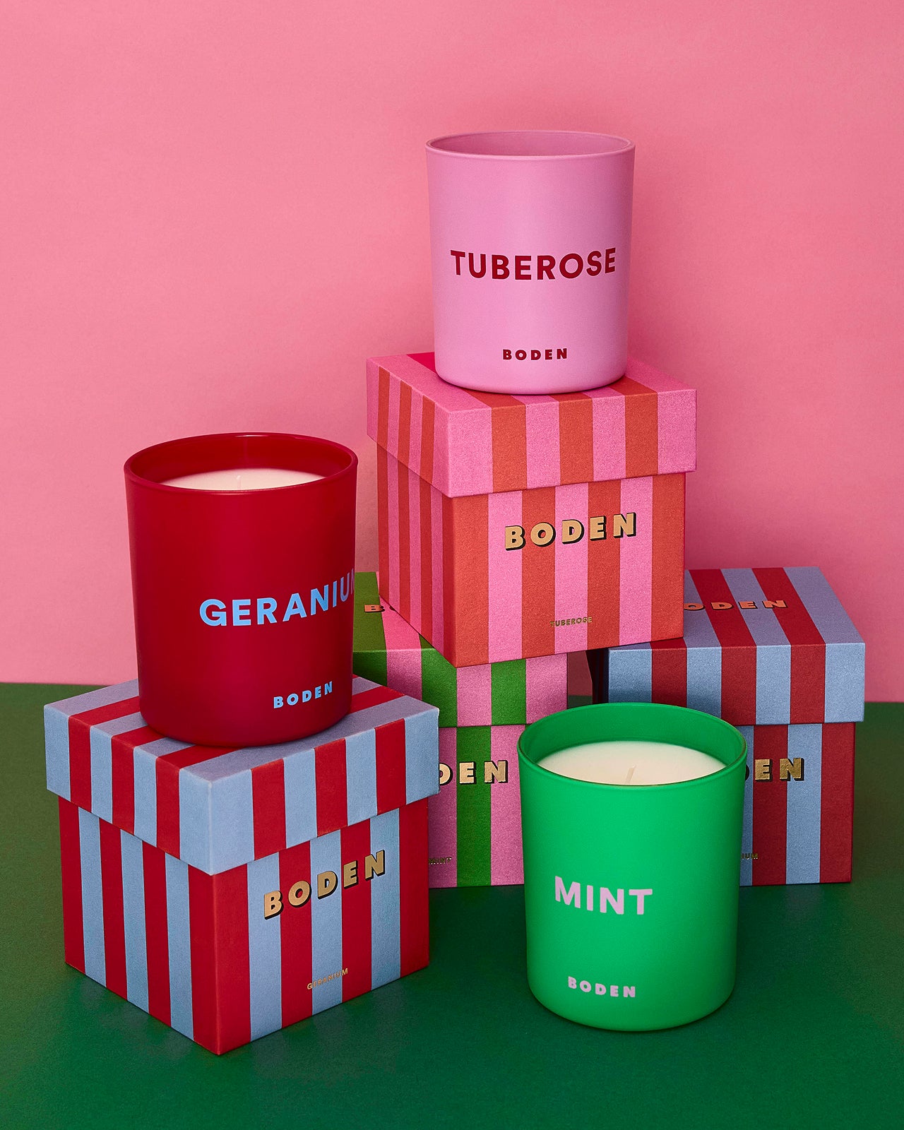 Boden candles in red, pink, and green with striped boxes on a pink background