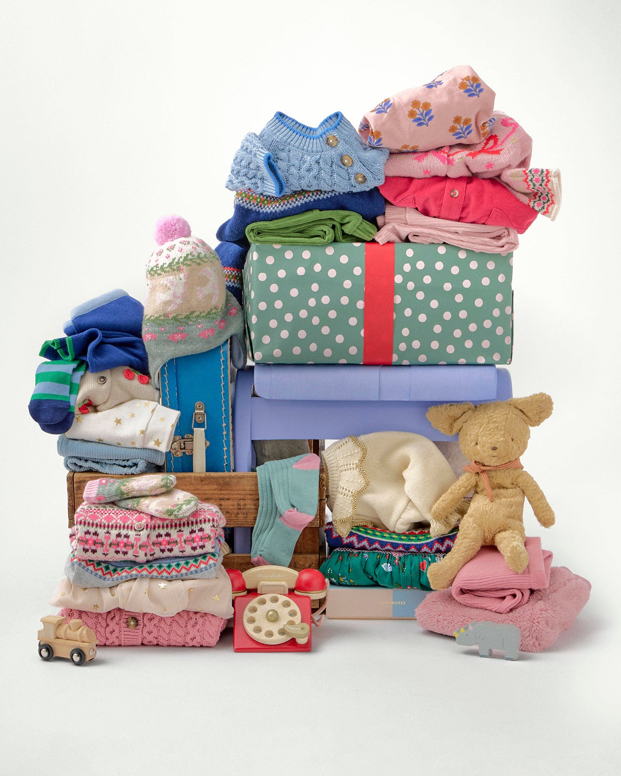 Stack of baby clothes and toys on a light blue background