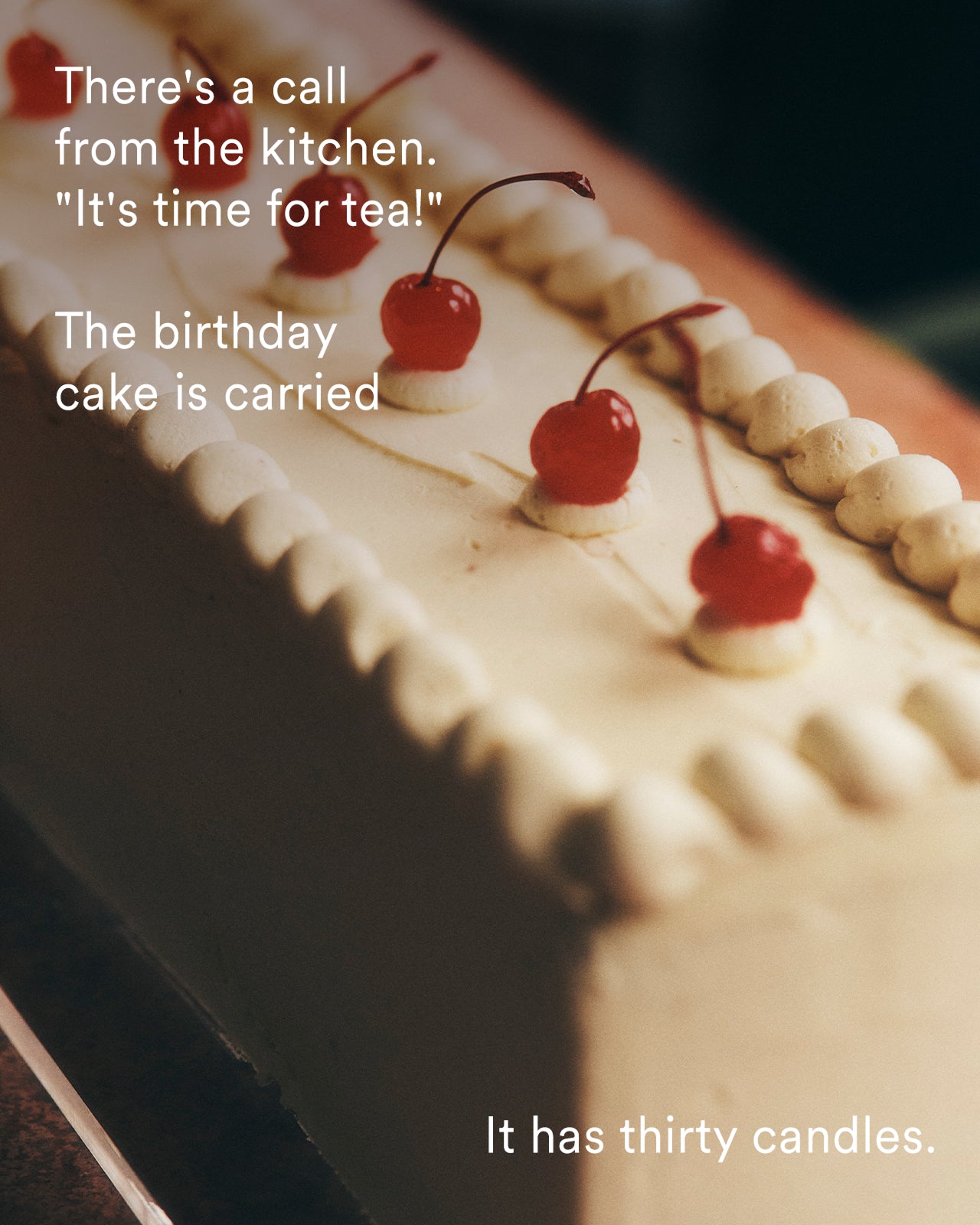 A close-up of a rectangular birthday cake with white frosting, piped borders, and three red cherries on top. White text overlays read, 'There's a call from the kitchen.