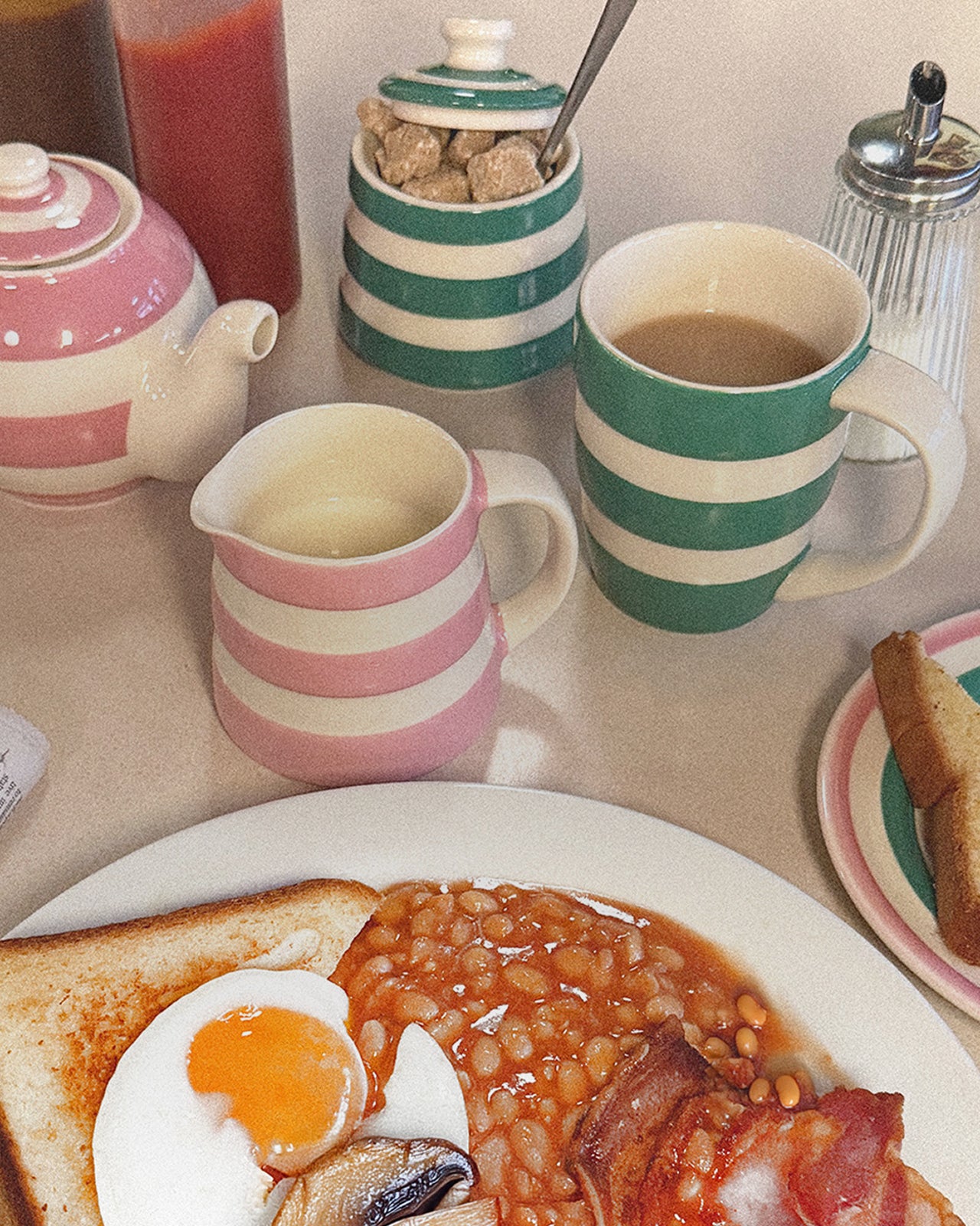 Breakfast scene with eggs, beans, toast, and coffee on a table.