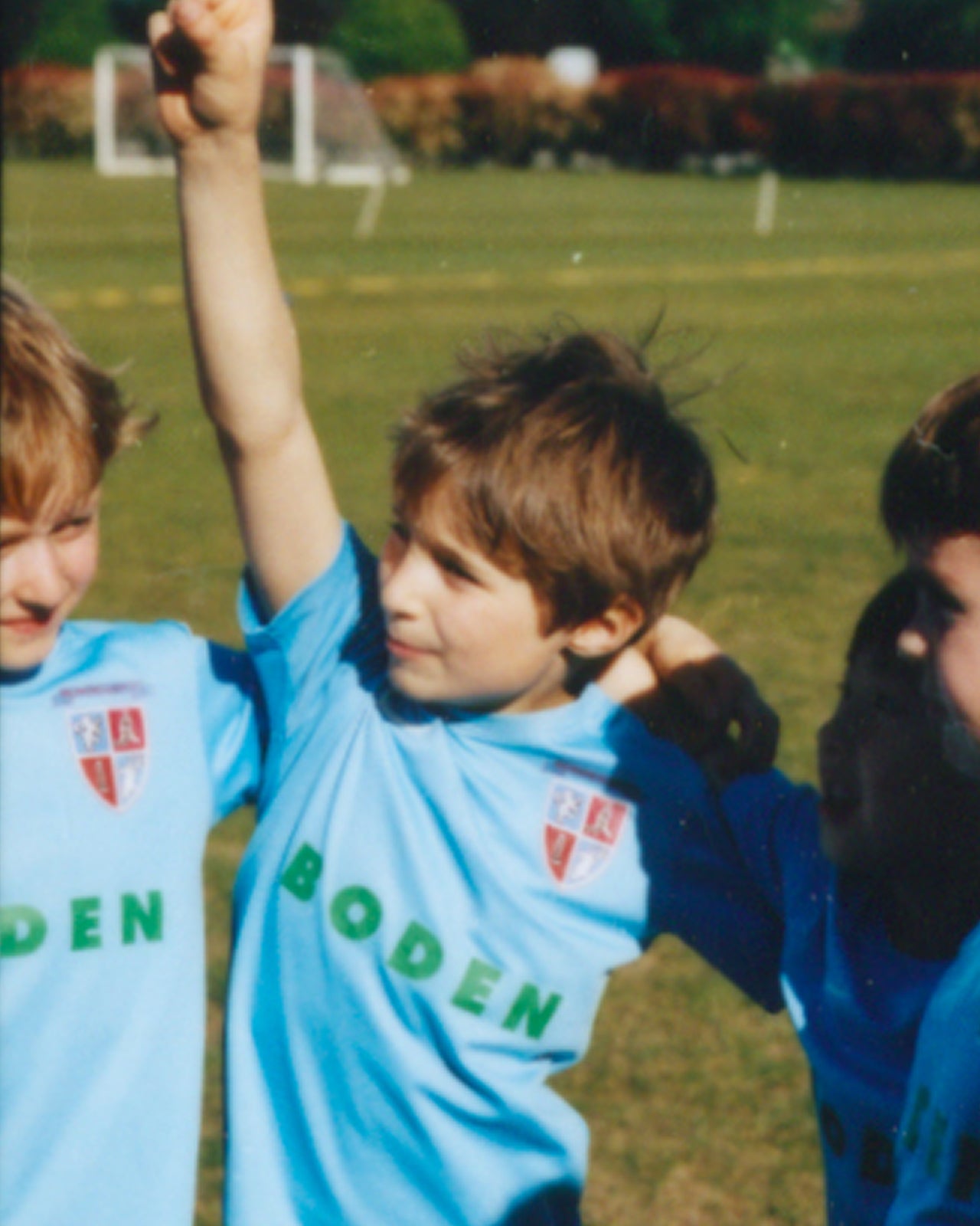 Children in light blue sports jerseys with 'Boden' logo on a grassy field.