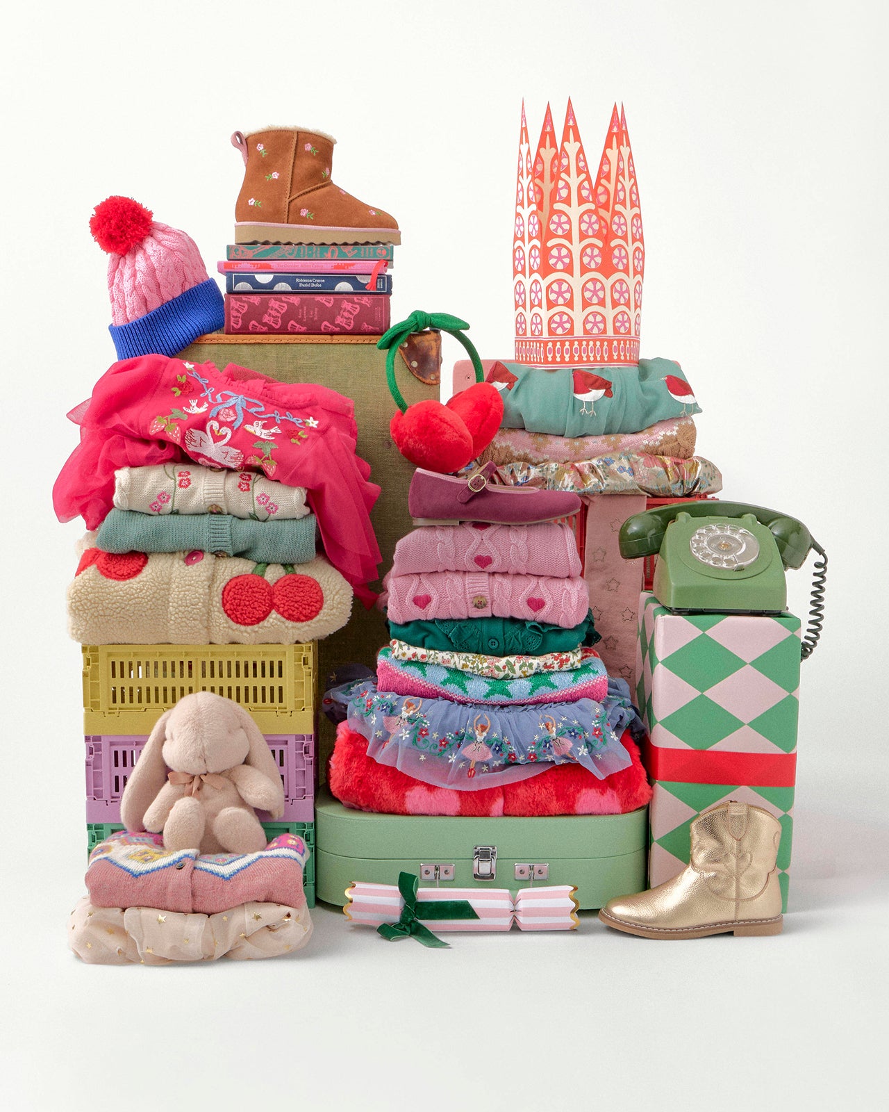 Stack of colorful children's items including clothes, toys, and a toy phone on a white background