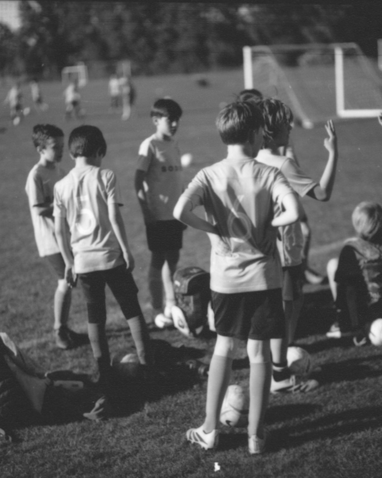 Children playing soccer on a field with a goal in the background