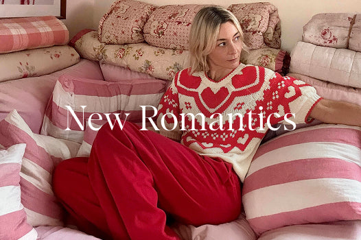 Person wearing a patterned sweater and red pants sitting on a pink couch with 'New Romantics' text.