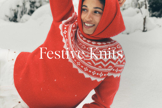 Person wearing a red knitted sweater with a patterned hood in a snowy setting, with 'Festive Knits' text overlay.