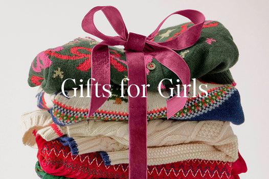 Stack of patterned sweaters tied with a pink ribbon on a white background with 'Gifts for Girls' text.