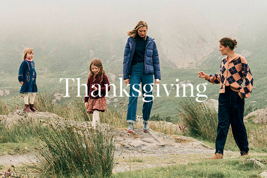 Four people standing on a rocky outcrop with 'Thanksgiving' text overlay, set against a misty landscape.