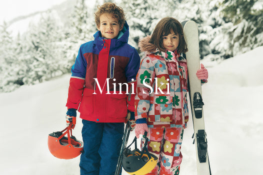 Two children in colorful snow gear walking in the snow with 'Mini Ski' branding.