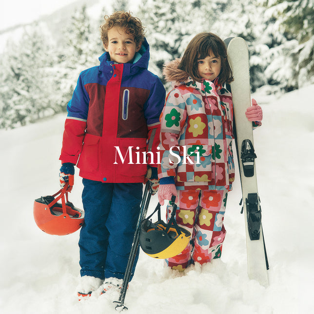 Two children in colorful snow gear walking in the snow with 'Mini Ski' branding.