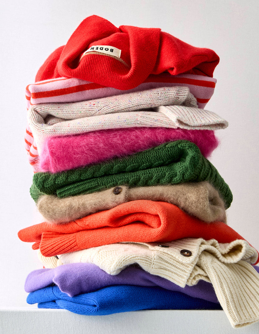 Stack of colorful folded sweaters on a white surface