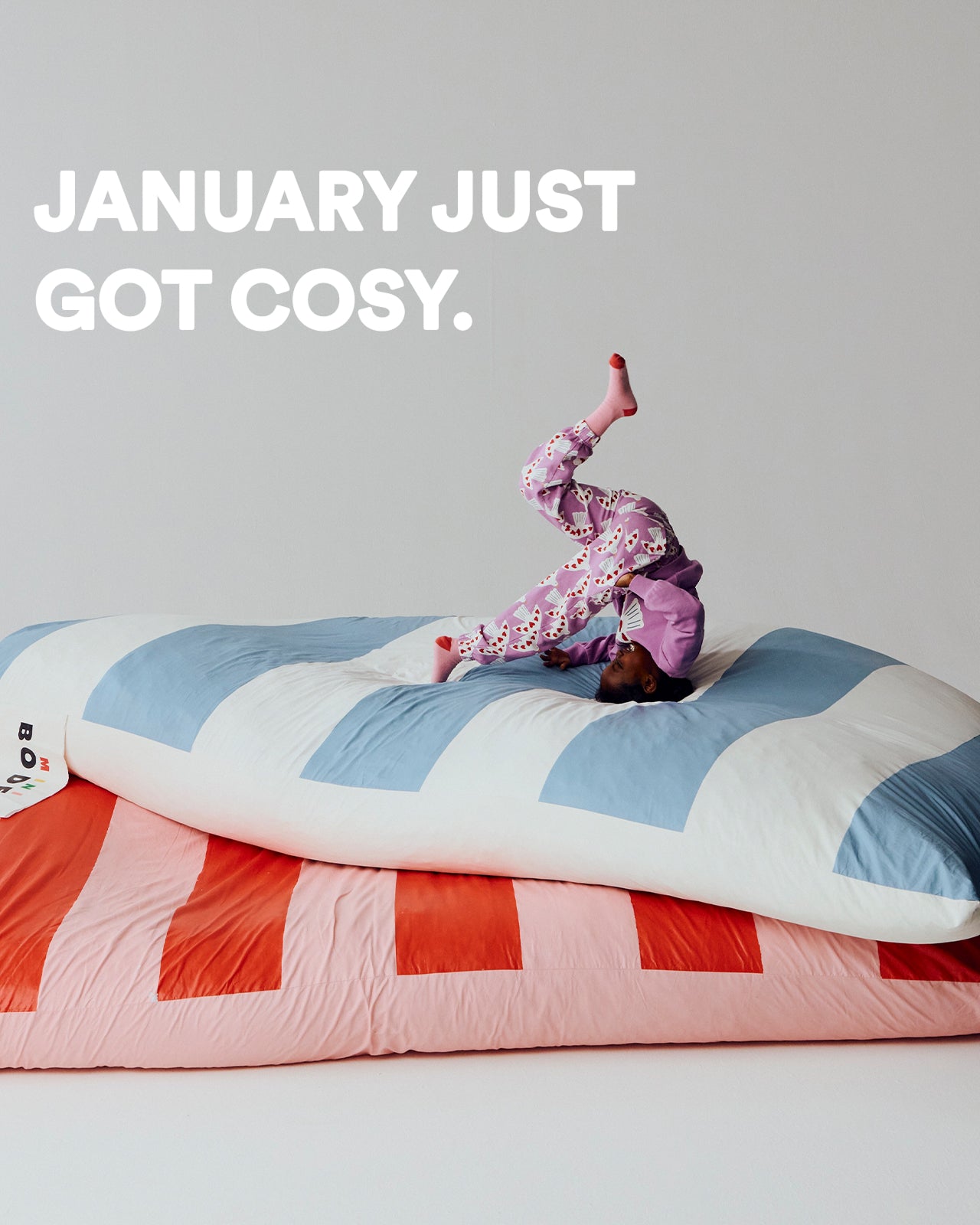 Person in pajamas standing on a colorful comforter with text 'January just got cosy' above.
