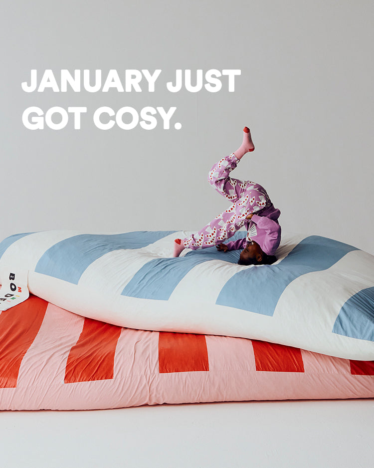 Child in pajamas on a colorful striped bed with text 'January just got cosy.'