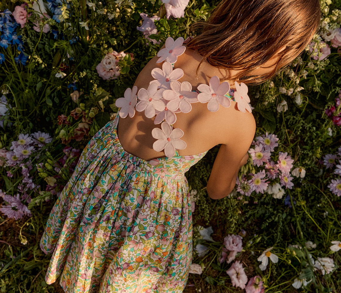 Girl in a floral dress lying among flowers with a floral-patterned back