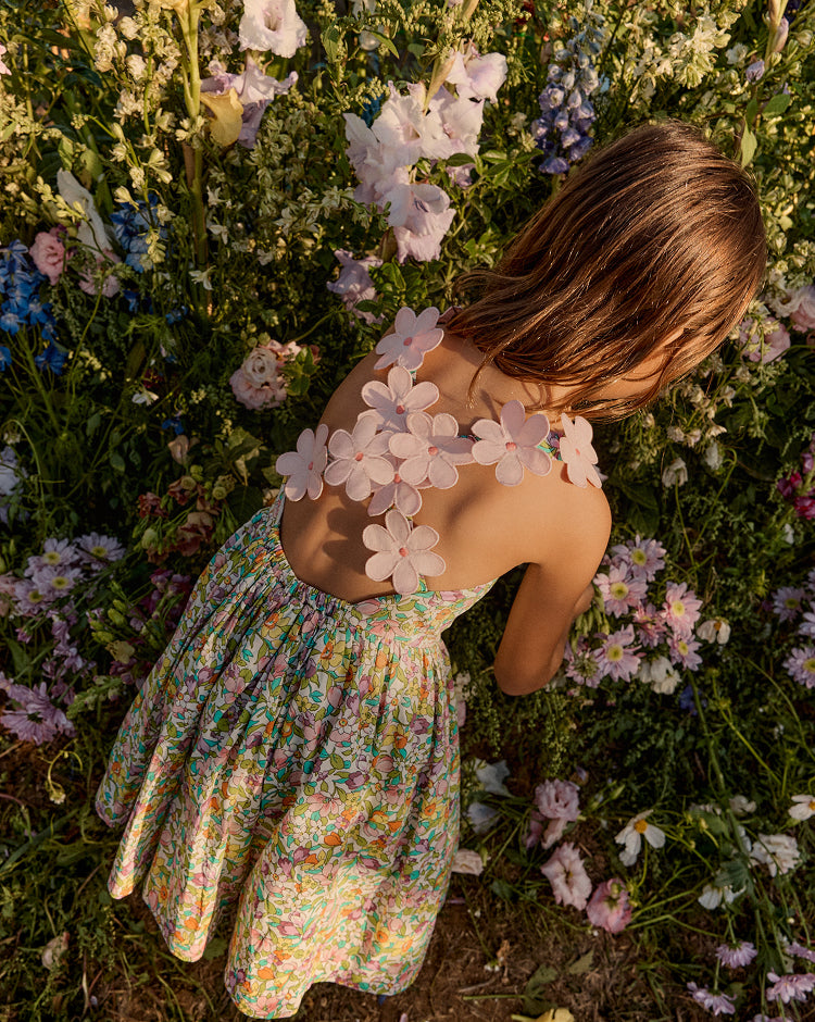 Girl in a floral dress lying among flowers with a floral-patterned back