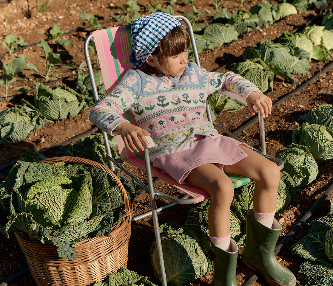 Child sitting on a chair in a garden surrounded by cabbages