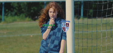 Person in a sports uniform standing on a field with a goalpost in the background