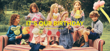 A group of six children sitting on a striped outdoor sofa holding balloon animals, with large yellow text reading 'IT'S OUR BIRTHDAY' across the center.