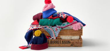Stack of colorful knitted items on a red surface with a blurred background