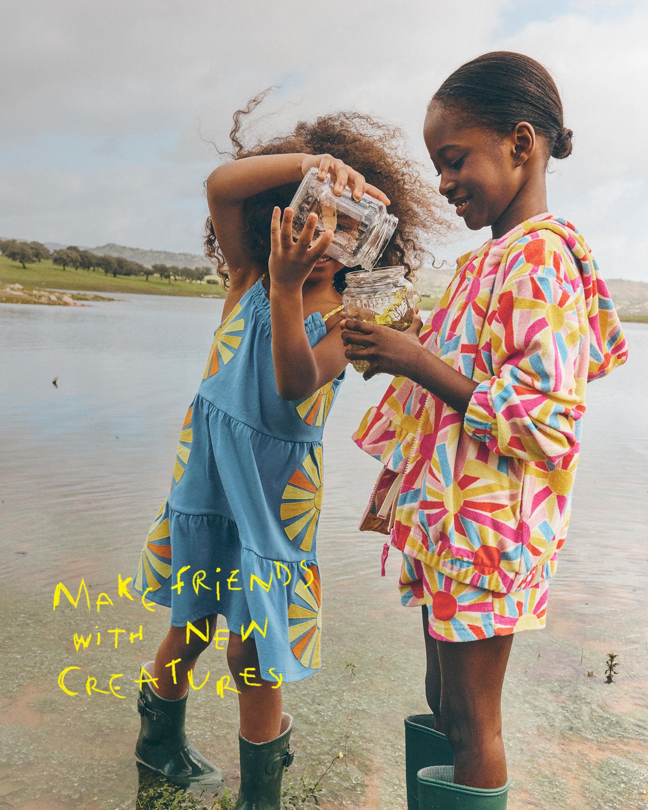 Two children by a lake holding jars, with text 'Make friends with new creatures' on a natural background.
