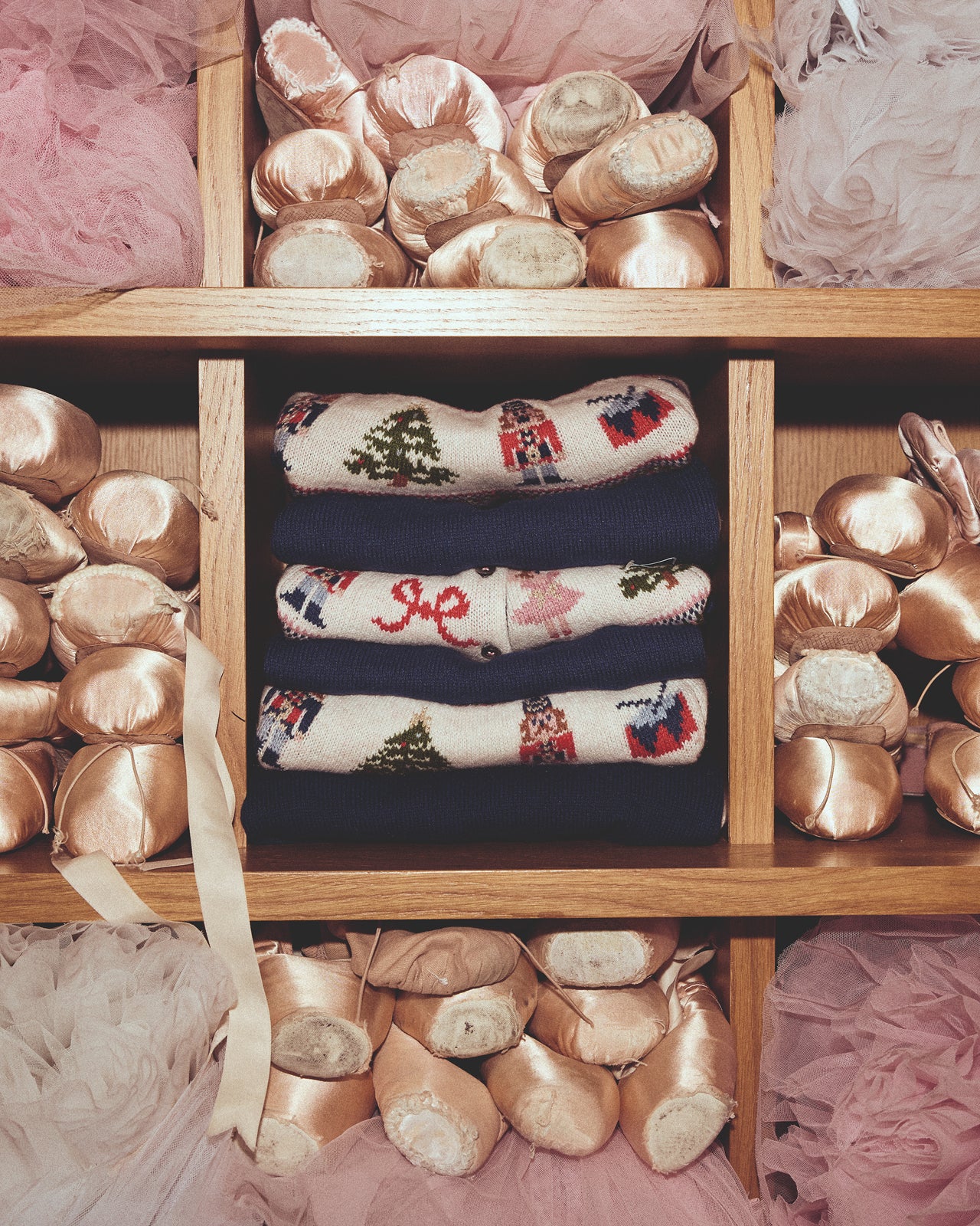 Wooden shelf with ballet shoes and decorative socks on a pink background