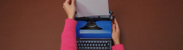 Person typing on a vintage typewriter with a plain background