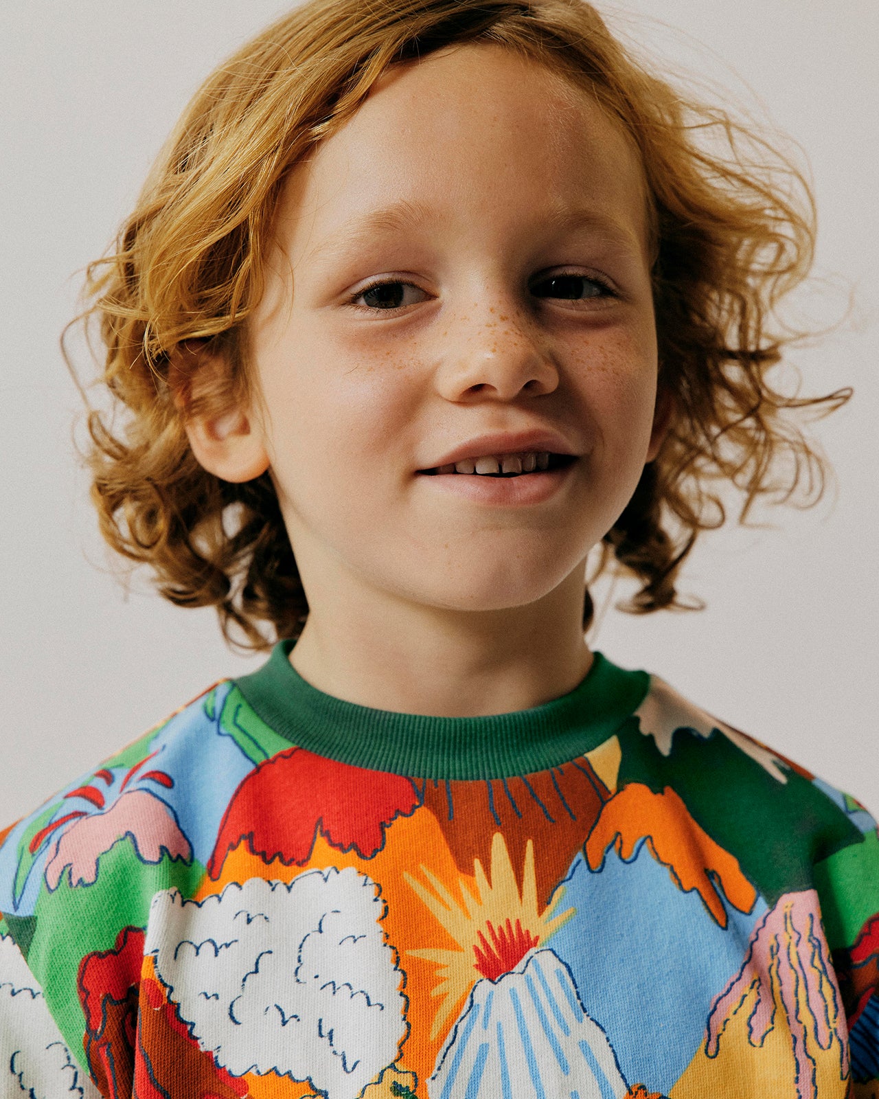 Child wearing a colorful sweater with abstract designs on a plain background