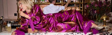 Woman in a purple satin dress sitting at a bar with a man behind the counter.