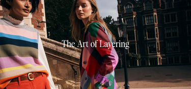 Two women wearing colorful outfits with a building in the background, featuring the text 'The Art of Layering'.