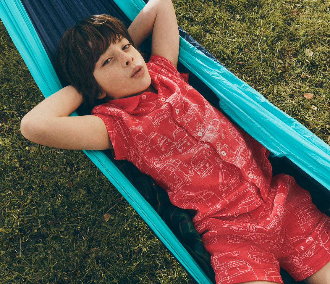 Child lying on a blue hammock in a grassy area