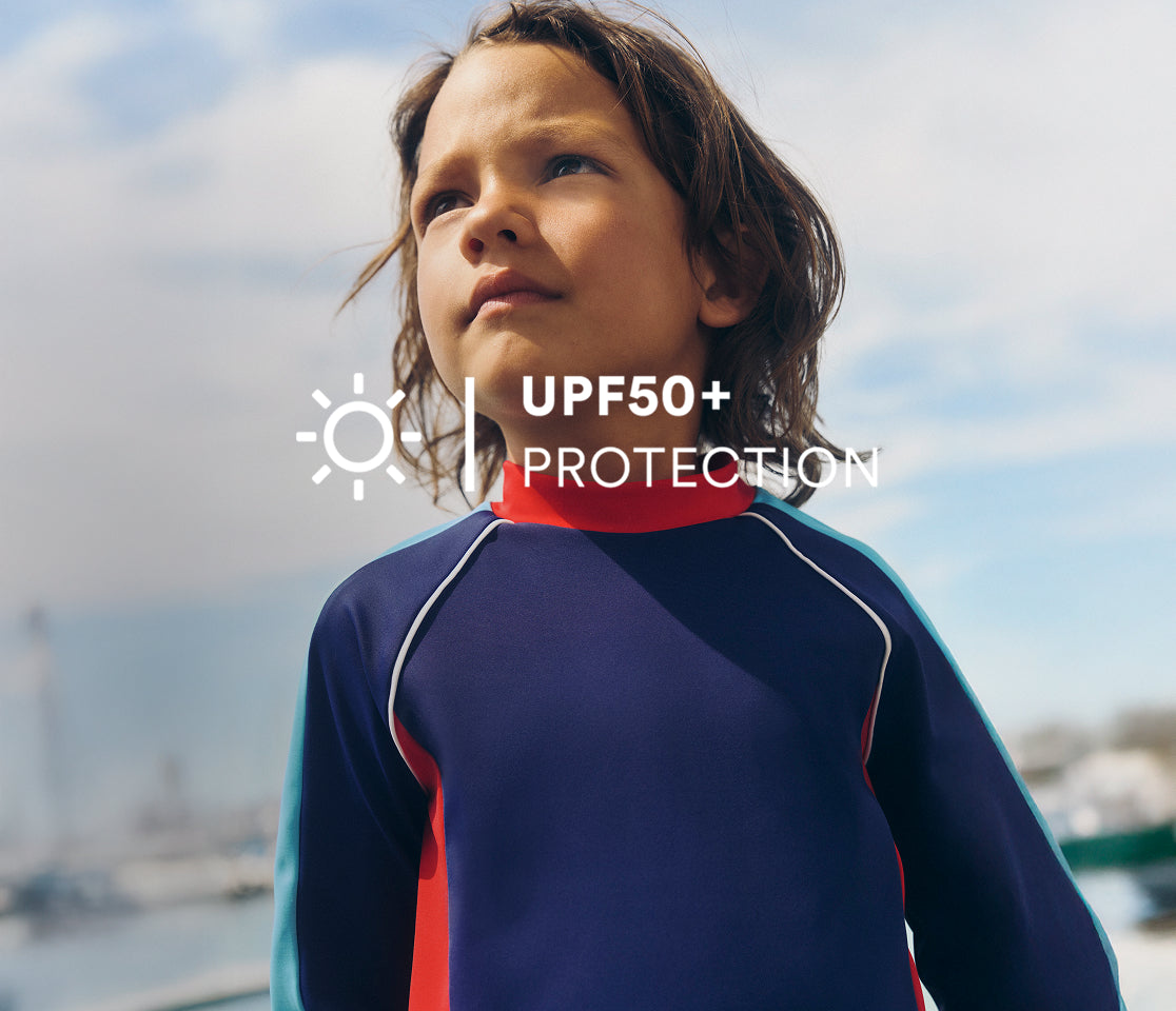 Child wearing a blue and red swimsuit with UPF50+ protection text overlay.