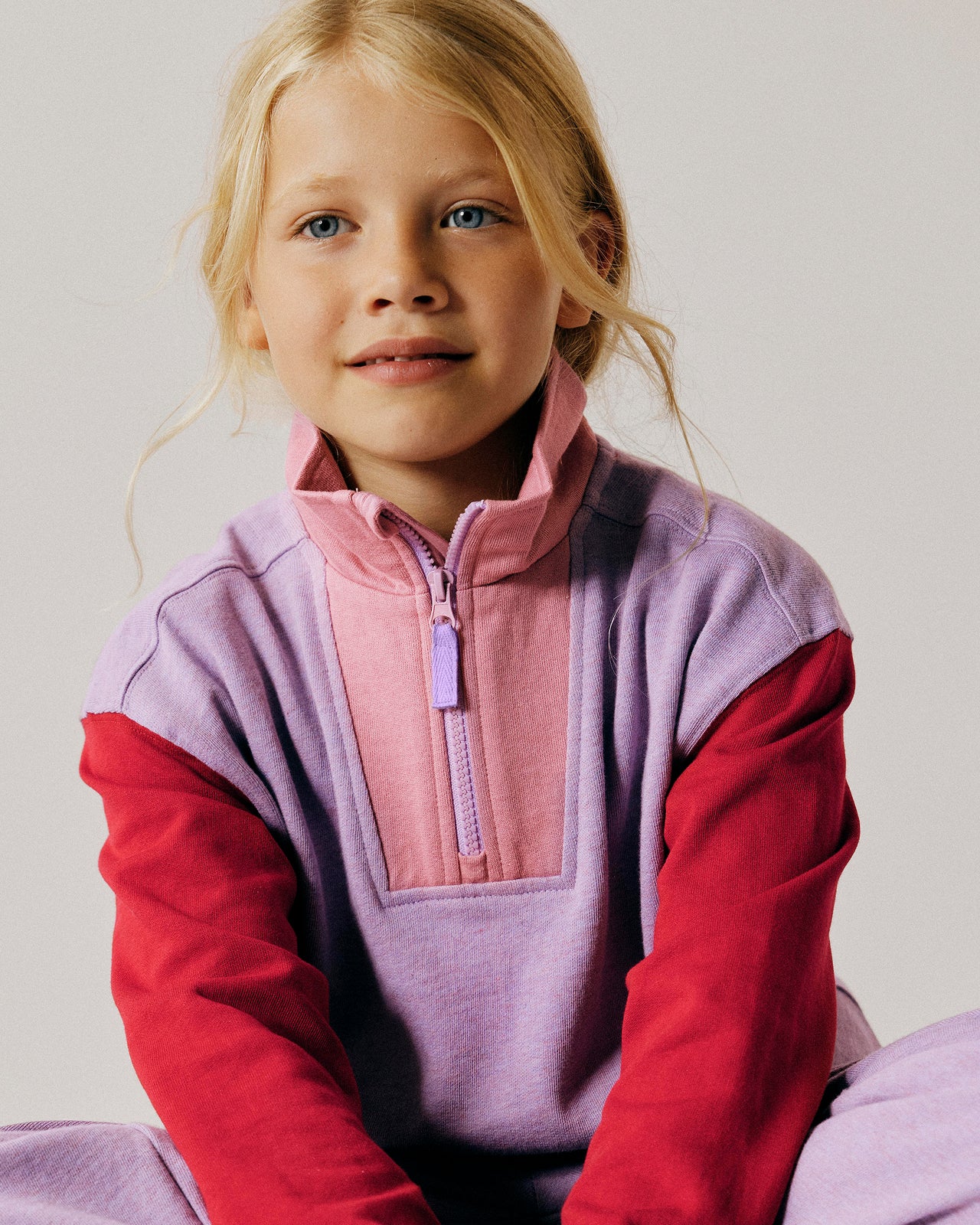 Young girl wearing a colorful fleece pullover against a plain background