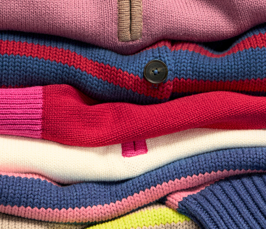 Stack of colorful striped sweaters with a button detail.