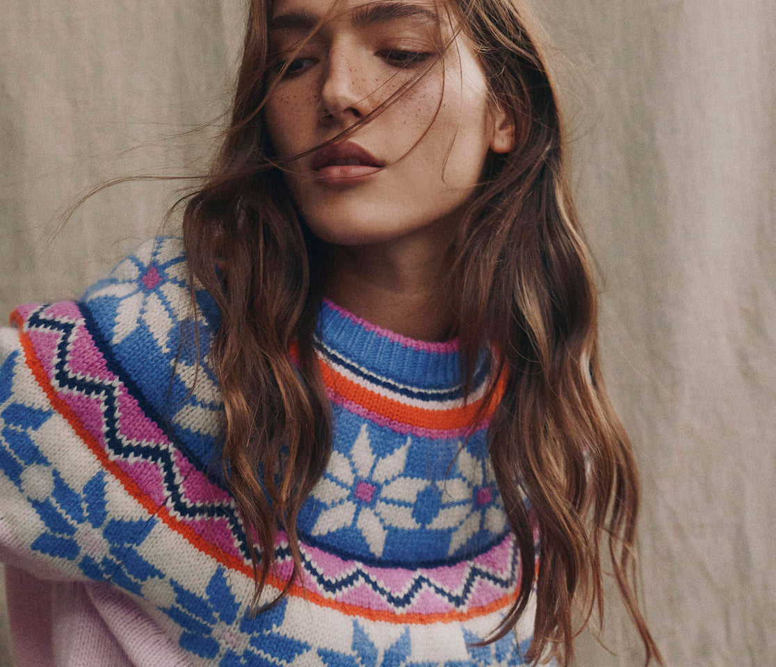 Woman wearing a colorful patterned sweater against a neutral background