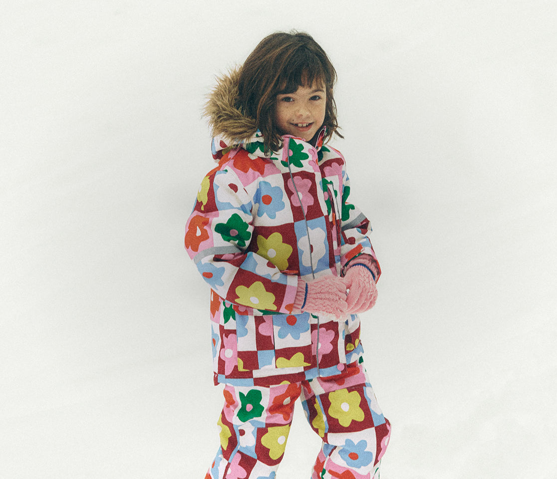 Child wearing a colorful floral-patterned snowsuit on a white background