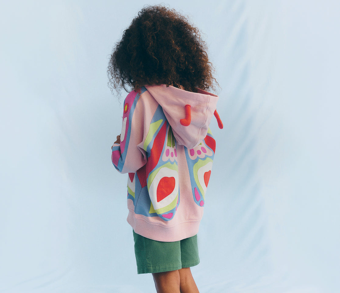 Person wearing a colorful hoodie with a butterfly design on a light blue background