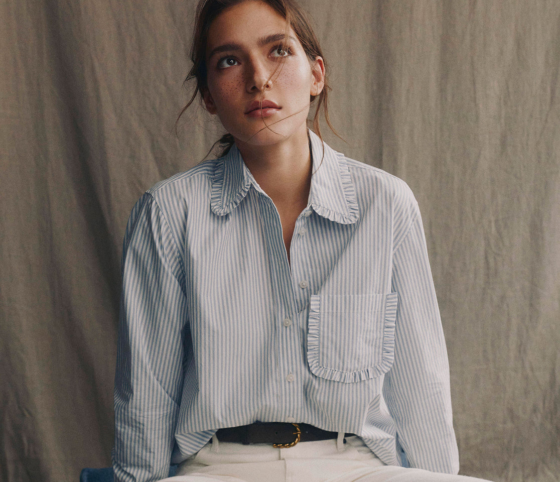 Woman wearing a light blue striped shirt against a neutral background