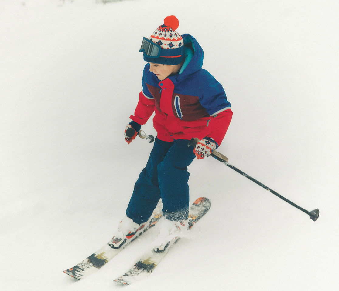Child skiing on a snowy slope wearing a colorful outfit