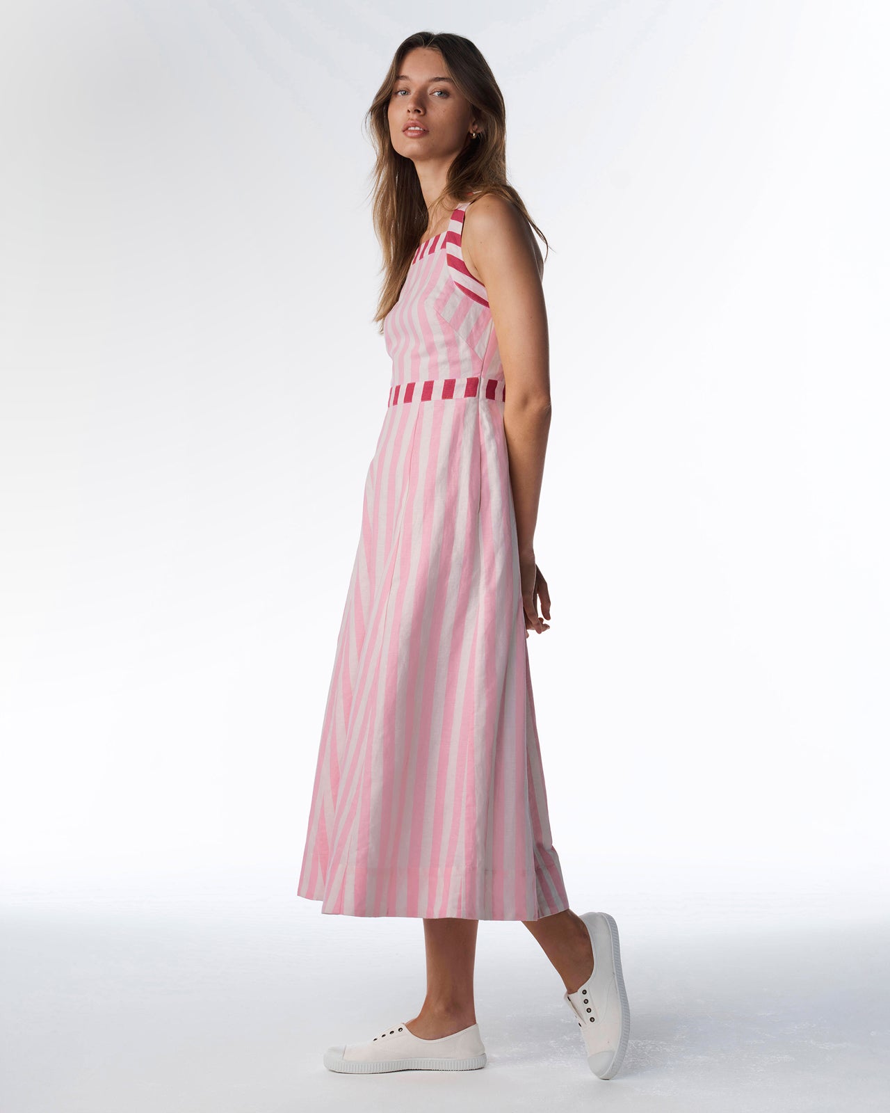 Woman wearing a pink and white striped dress on a white background