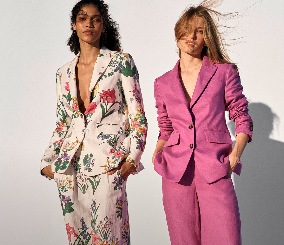 Two women wearing colorful suits against a plain background