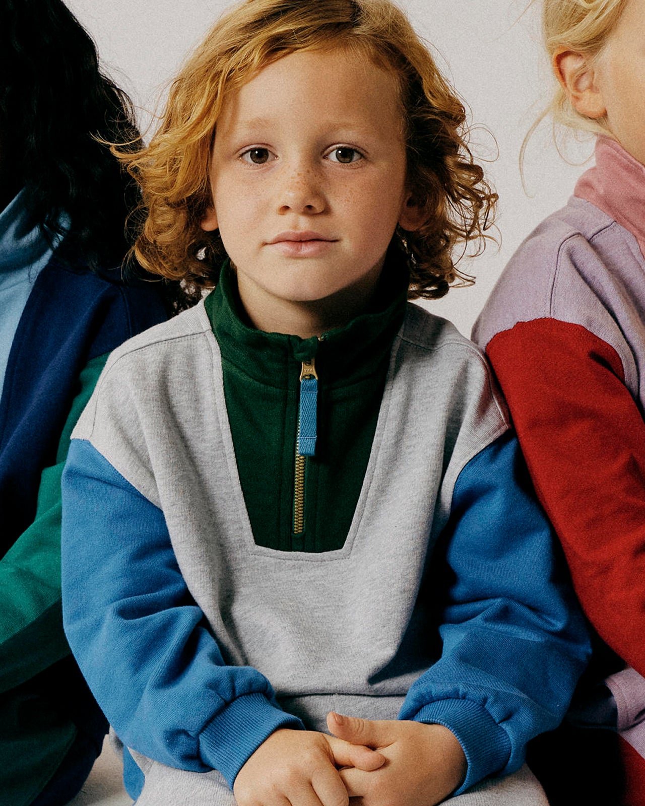 Child wearing a colorful sweater with a neutral background