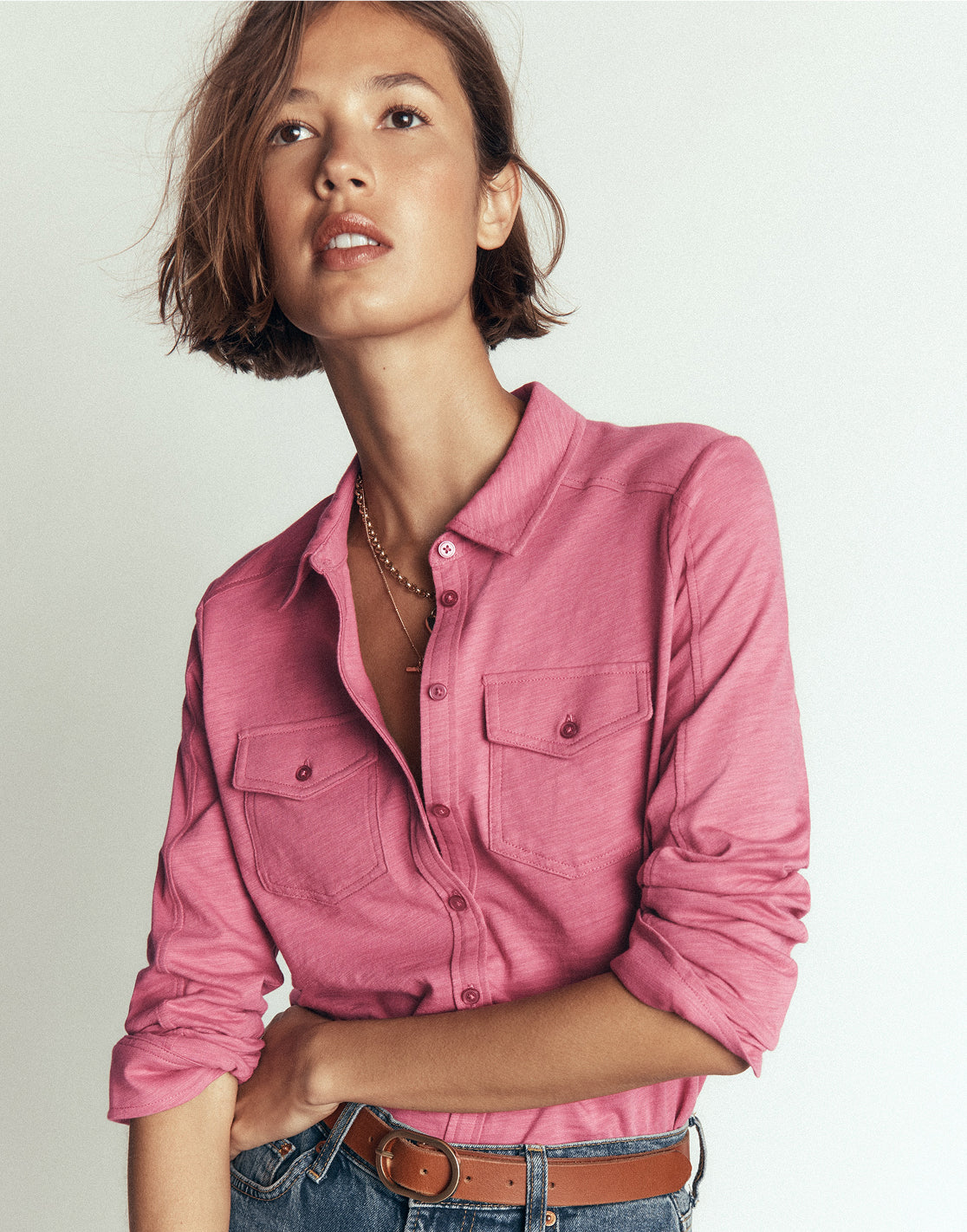 Person wearing a pink shirt and jeans on a plain background