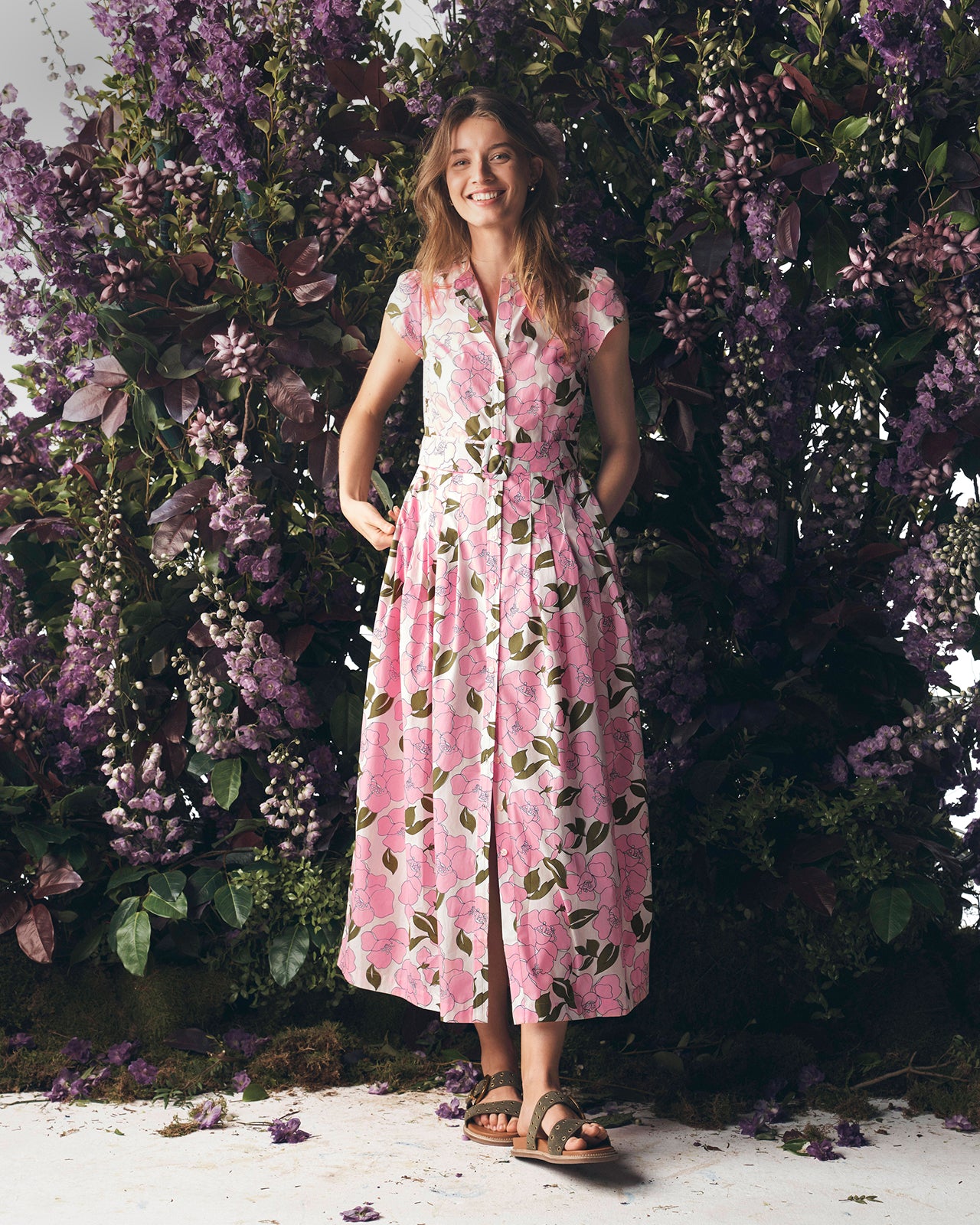 Woman in a pink floral dress standing among purple flowers