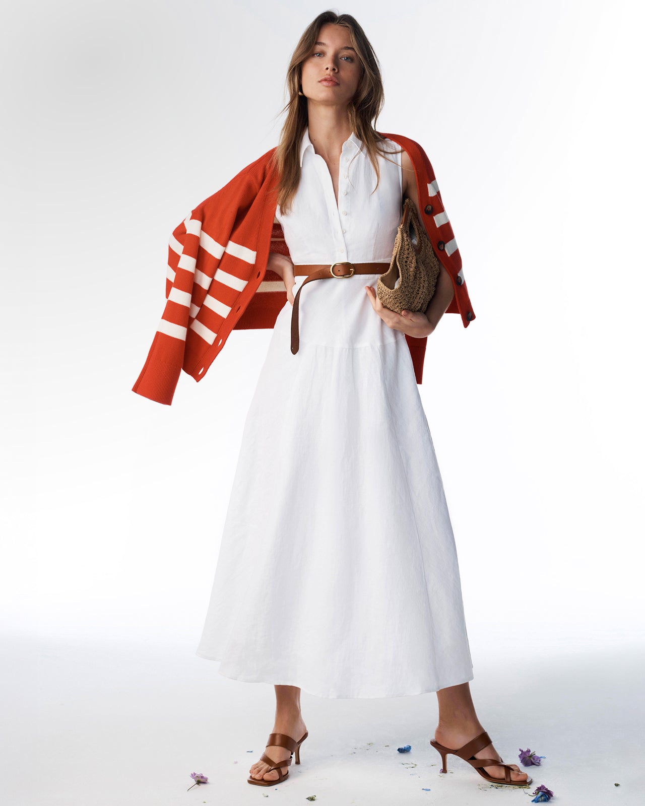 Woman wearing a white dress with a red and white striped cardigan on a white background