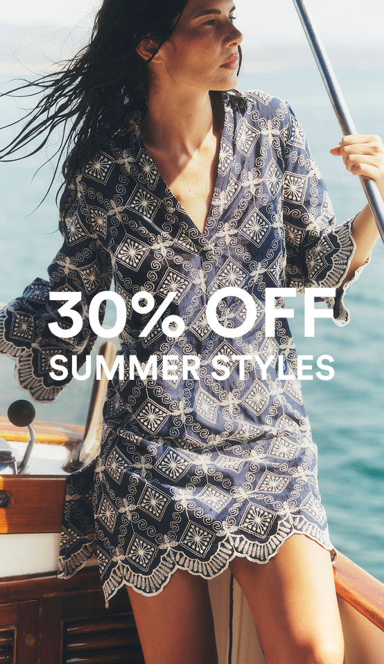 Woman on a boat wearing a patterned dress with a promotional text overlay for summer styles sale.