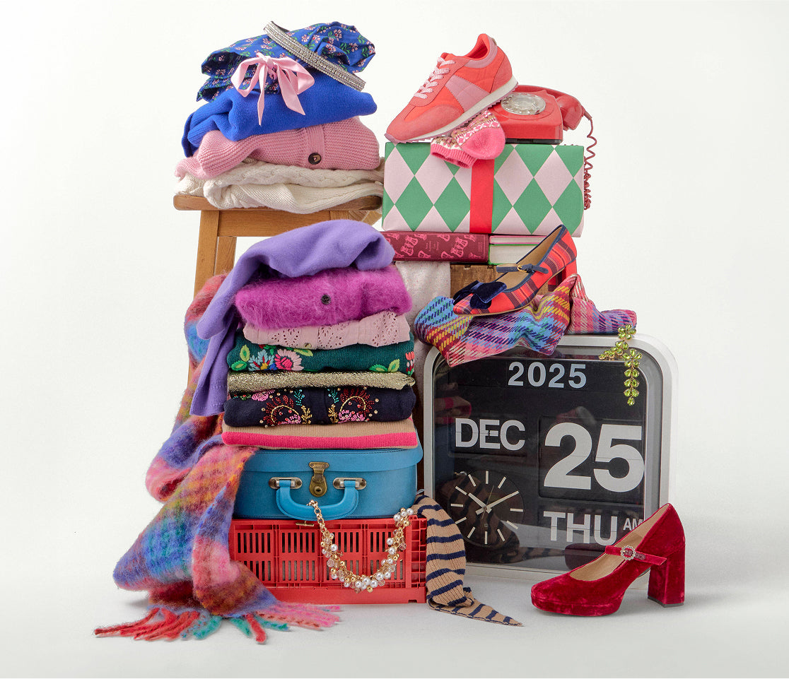 Stack of clothes, shoes, and accessories with a calendar indicating December 25th on a white background.