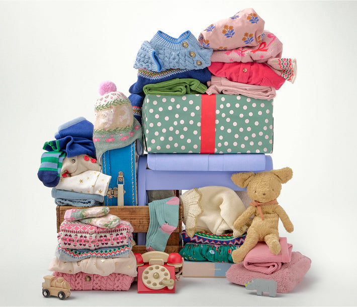 Stack of baby clothes and toys on a white background