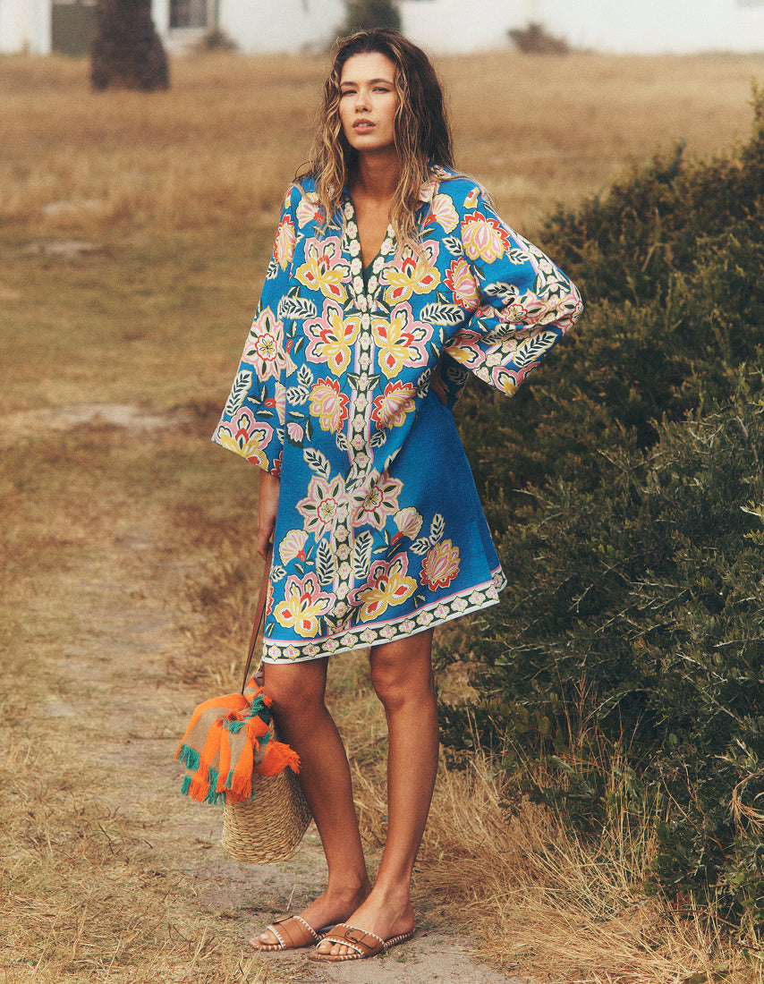 Woman wearing a colorful floral dress standing outdoors in a natural setting