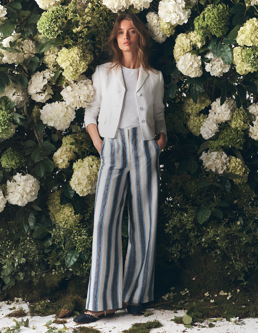 Woman in a white jacket standing in front a flower garden